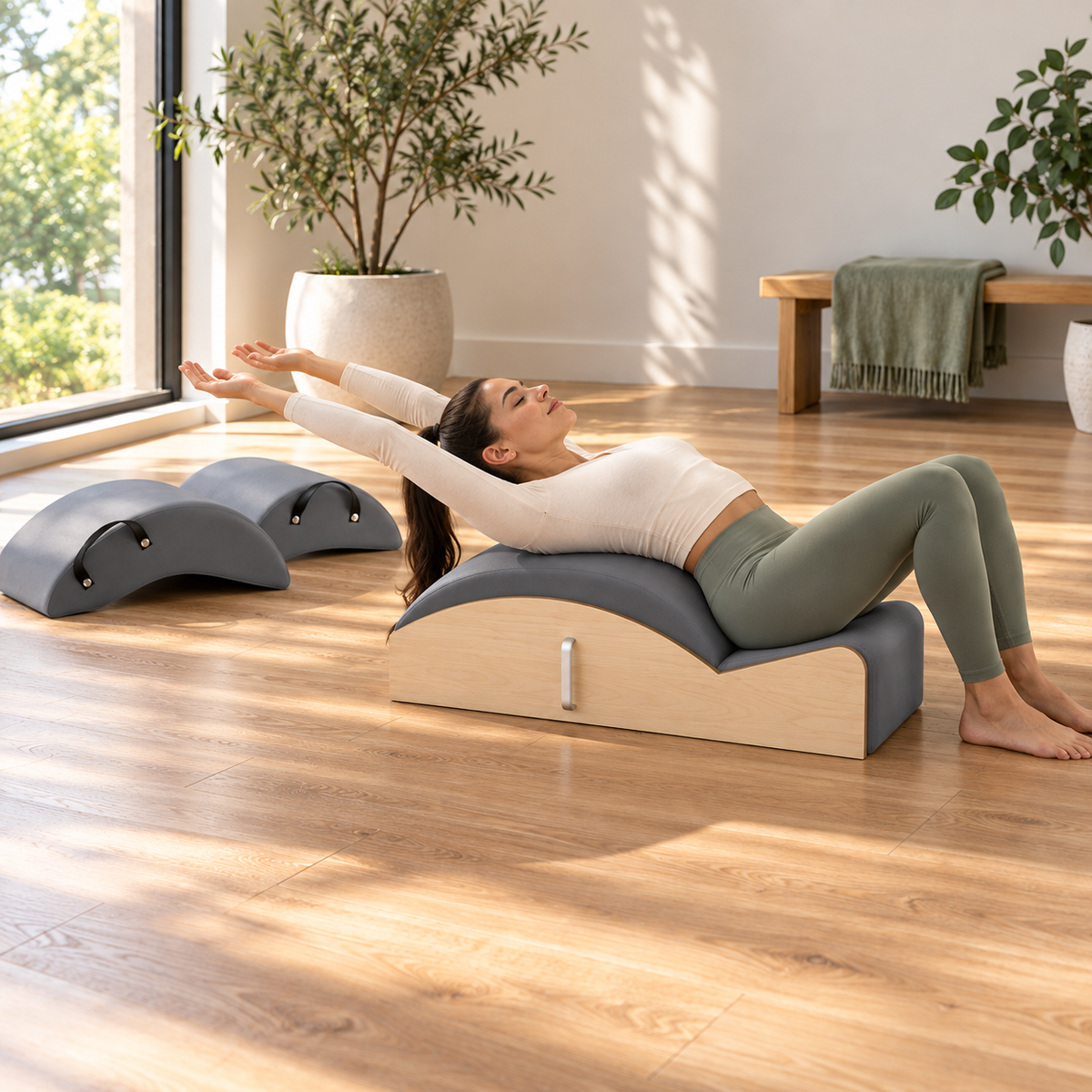 Woman in a back extension over the base of the Elina Pilates Spine Corrector 3 in 1 with the two arc shells beside her
