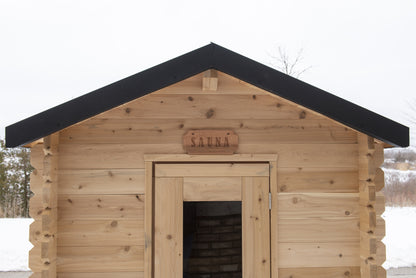 Front elevation of the Granby Cabin Sauna showing the gable roof, cedar door and carved SAUNA plaque