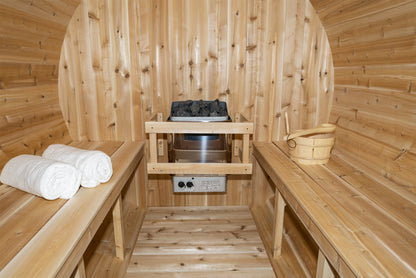 Inside the barrel sauna showing the parallel cedar benches and the included electric heater with rocks