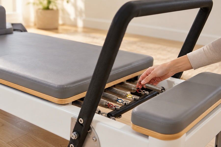Hand adjusting a spring on a Pilates reformer